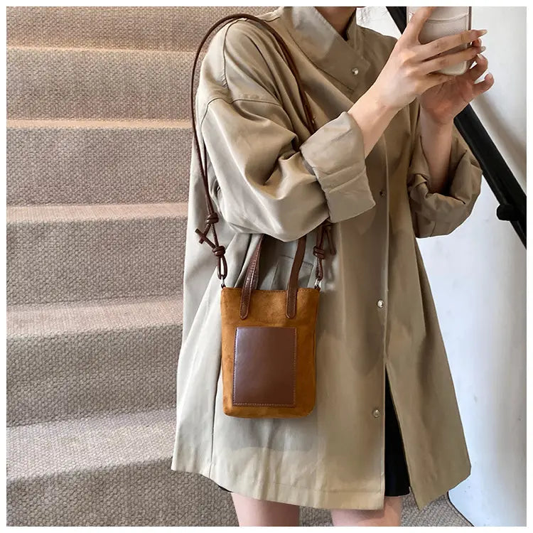 Tan suede mini bucket crossbody bag with a contrasting brown leather patch and matching straps in a retro leopard print design.