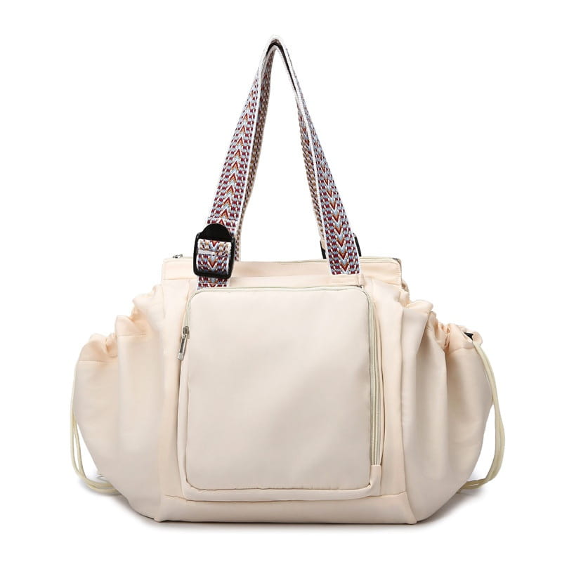 Cream-colored multifunctional waterproof nylon fashion tote and backpack with patterned shoulder straps and a front zippered pocket.