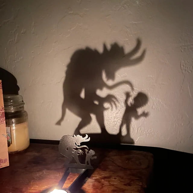 black metal halloween bat candle holder with intricate metallic shadow puppet design of a creature and child casting dramatic silhouette on the wall.
