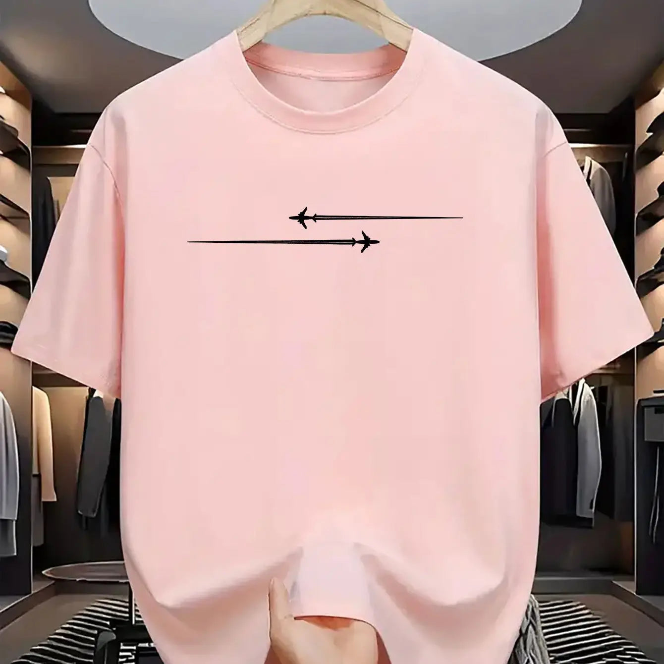 A soft pink minimalist airplane graphic cotton blend sport t shirt with short sleeves and two black airplanes flying in opposite directions on the chest.