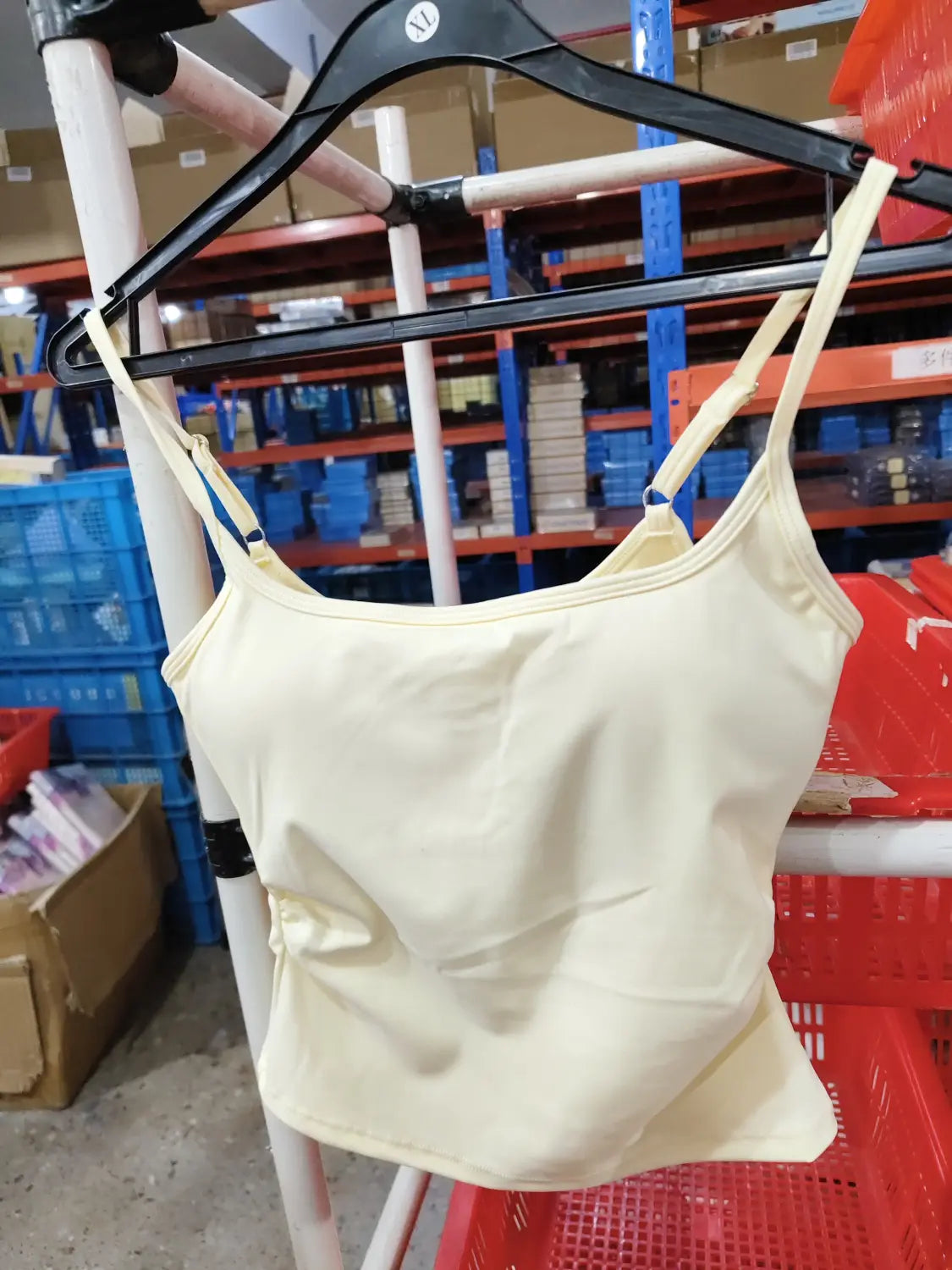 Camiseta sin mangas acolchada color amarillo pálido con tirantes finos, confeccionada con tela lisa de secado rápido, diseñada para ropa deportiva de entrenamiento.