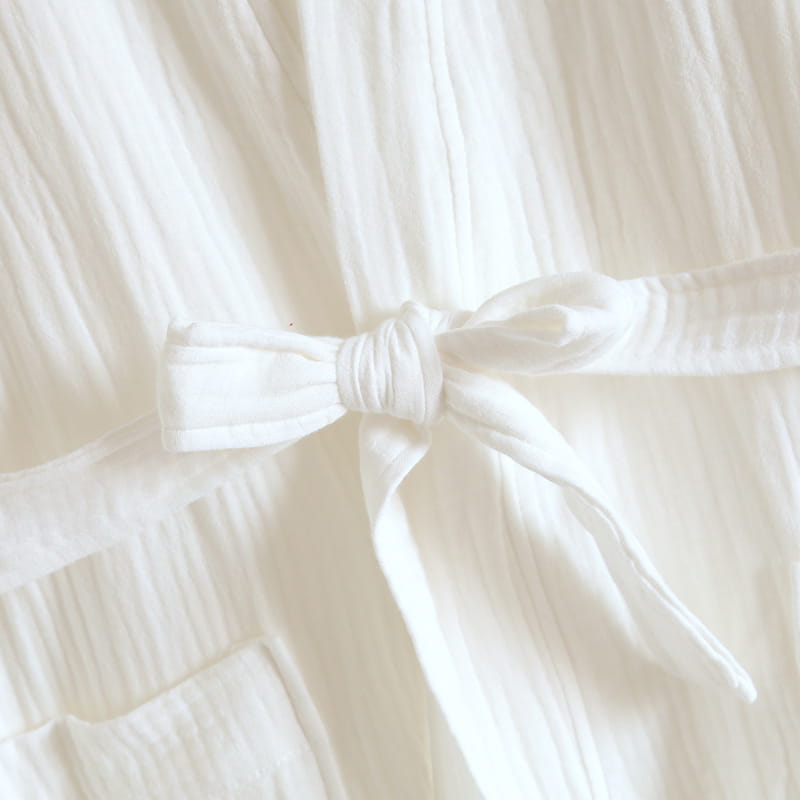 Un délicat peignoir en gaze de coton blanc pour homme noué en un joli nœud, avec des plis souples et froncés