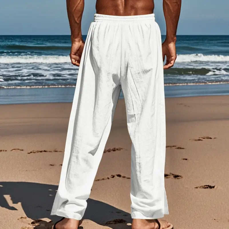 Men’s white loose-fitting linen beach pants with elastic waistband side pockets and straight leg design featuring side button detail.