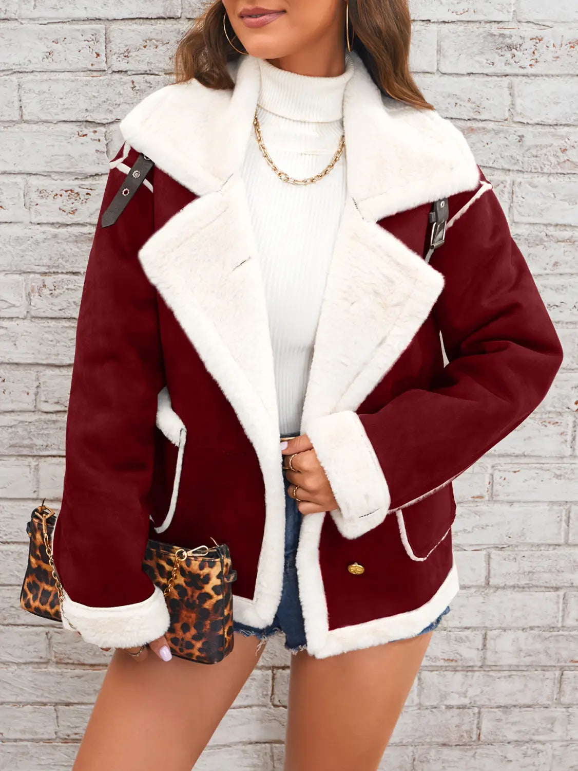 Veste bombardier en peau lainée moelleuse bordeaux, avec bordure en fourrure blanche et quincaillerie couleur ton or, conçue pour un vêtement d'hiver décontracté et chaud.