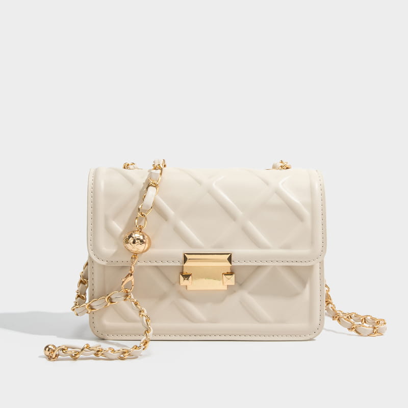 Cream-colored quilted crossbody bag with gold-tone chain strap and clasp in elegant leather design.