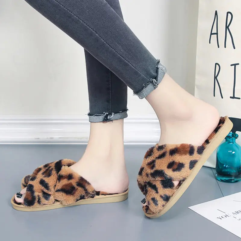 Leopard fuzzy cross strap plush house slippers with leopard print fuzzy texture and tan soft soles.
