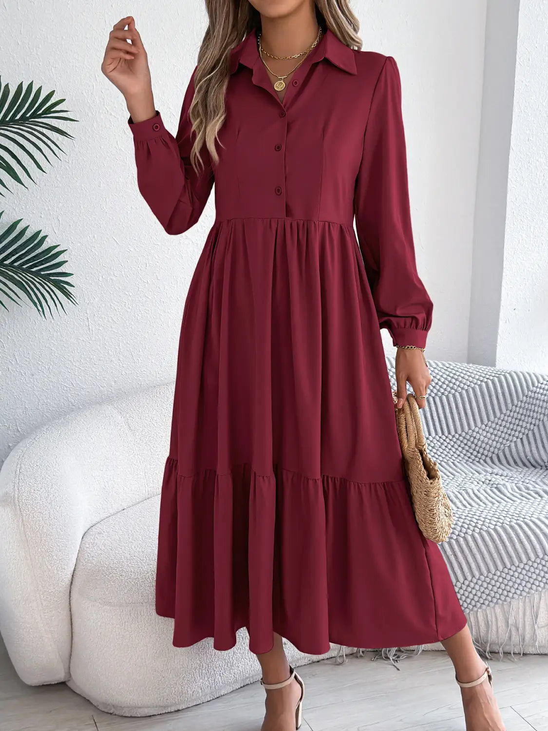 A flowing burgundy midi dress with long sleeves, a button-front collar, and a tiered skirt designed for women.