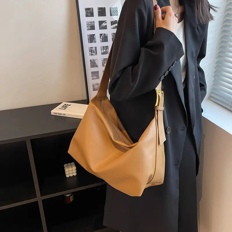 A tan leather shoulder bag with a gold-tone buckle and an adjustable strap suitable for daily use.