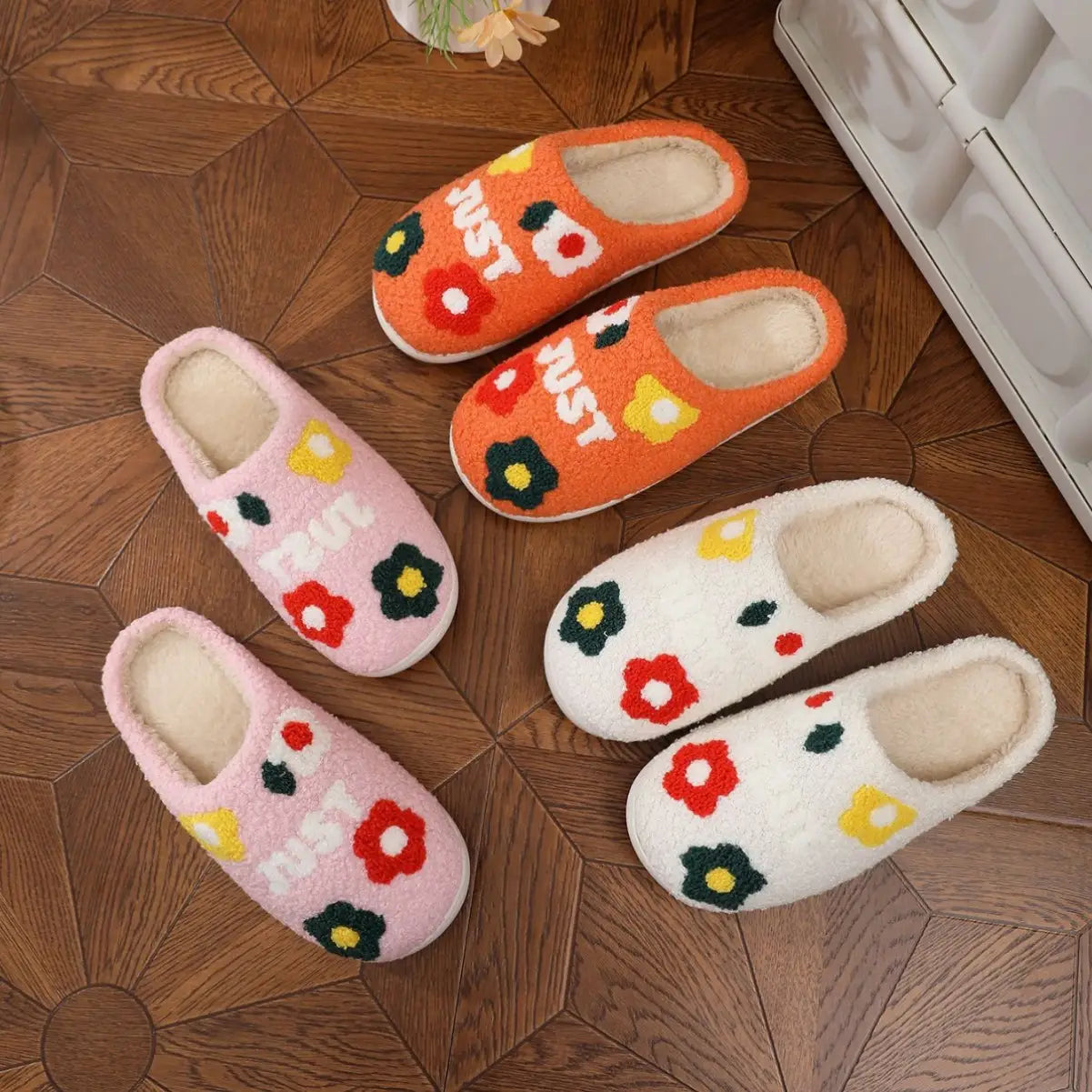 Set of three plush floral cotton slippers in pink orange and white with soft tpr sole and colorful floral embroidery each stitched with the word just.