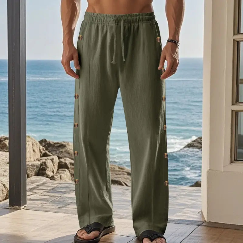 Men’s olive green linen straight leg pants featuring decorative wooden buttons down each leg seam.