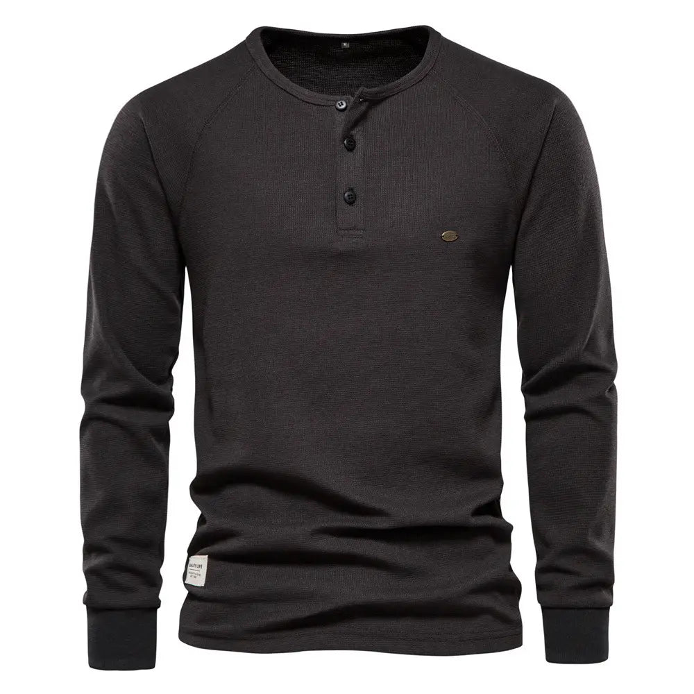 Chemise henley à manches longues côtelée pour homme, de couleur noire, avec un tissu texturé et trois boutons noirs.