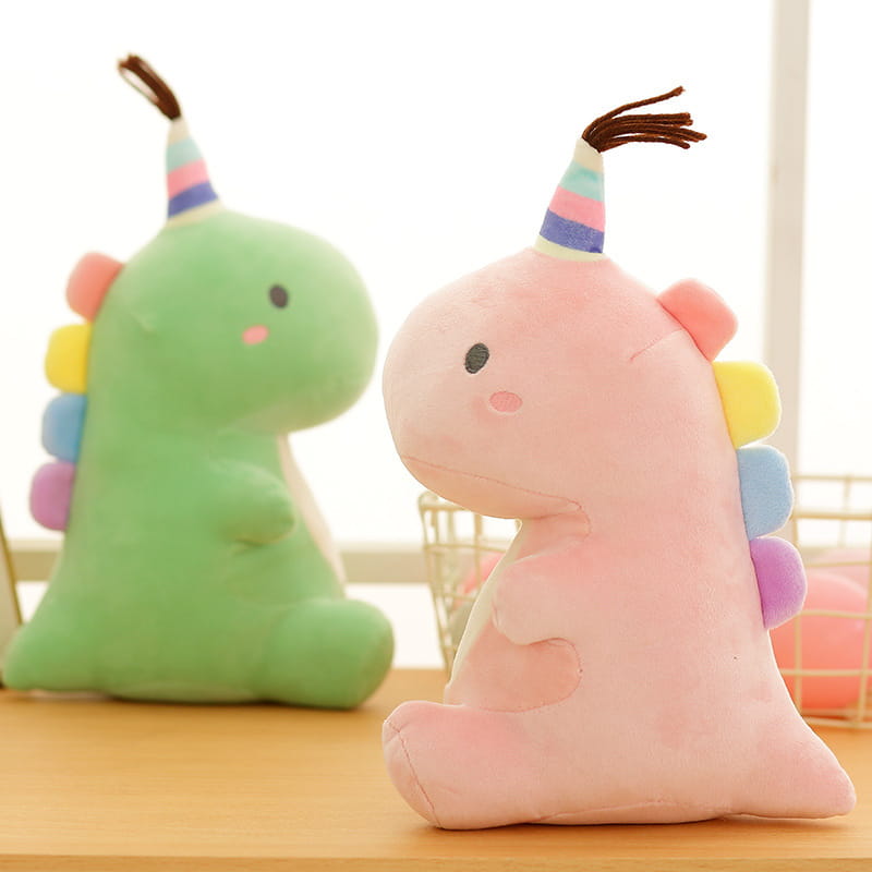 Ein pinkfarbener Plüsch-Dinosaurier als weiches Kuscheltier mit regenbogenfarbenen Stacheln und einer gestreiften Party-Kappe für festliches Spiel.