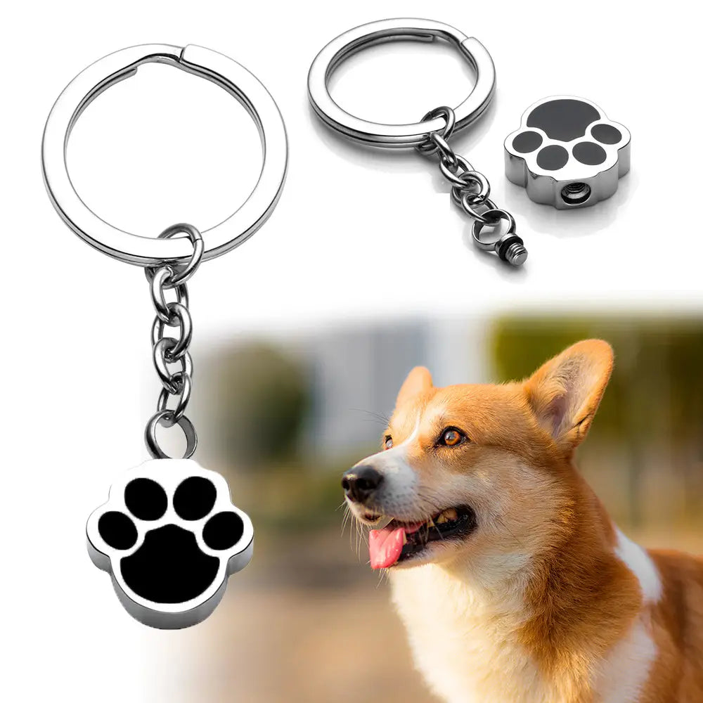 Silver dog paw urn keychain with black enamel inlay featuring a paw print design for cremation memorial purposes.