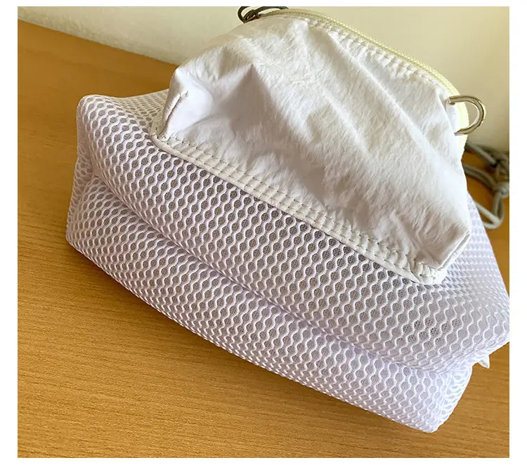 White mesh laundry bag with a solid white fabric top and silver-toned metal zipper pull featured in a mini pink mesh drawstring bucket bag with heart charm product.