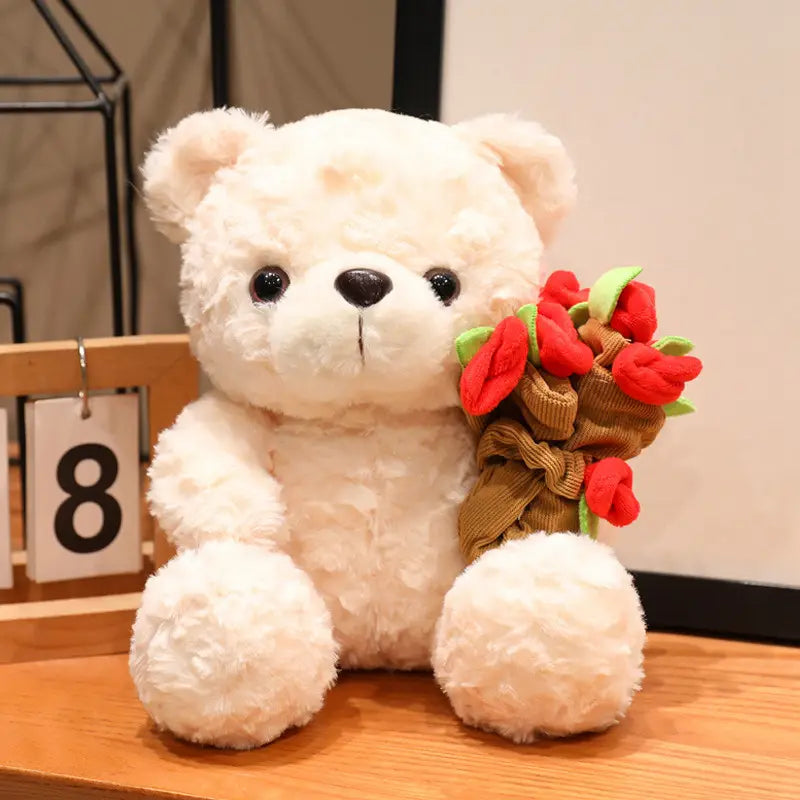 Ein weicher, cremefarbener Plüsch-Teddybär mit schwarzen Knopfaugen hält rote Stofftulpen, gebunden mit braunem Kordelband, als Valentinsgeschenk, Größe 16–25 cm.