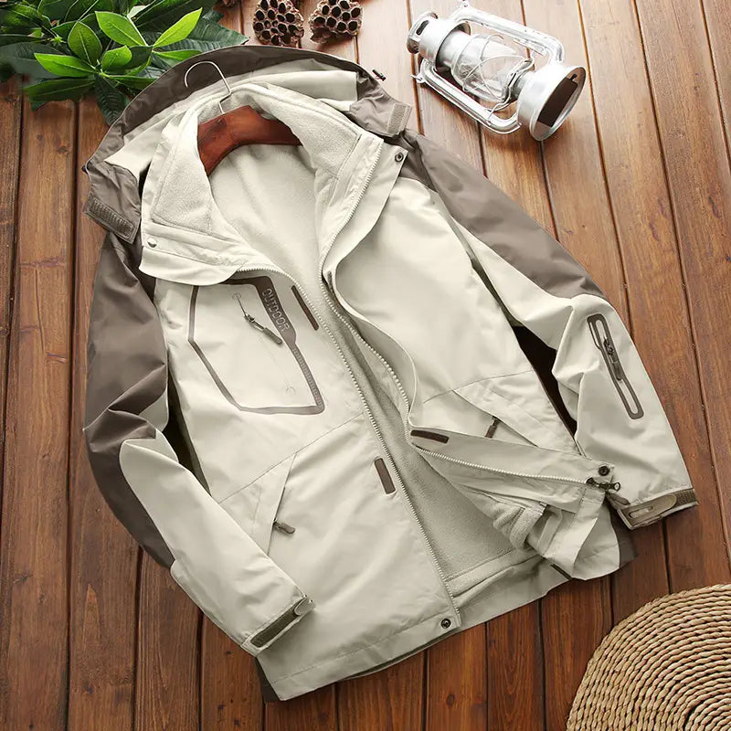 Men three-in-one waterproof winter sportswear jacket in beige and gray with a hood, zippered pockets, and reinforced seams designed for outdoor use.