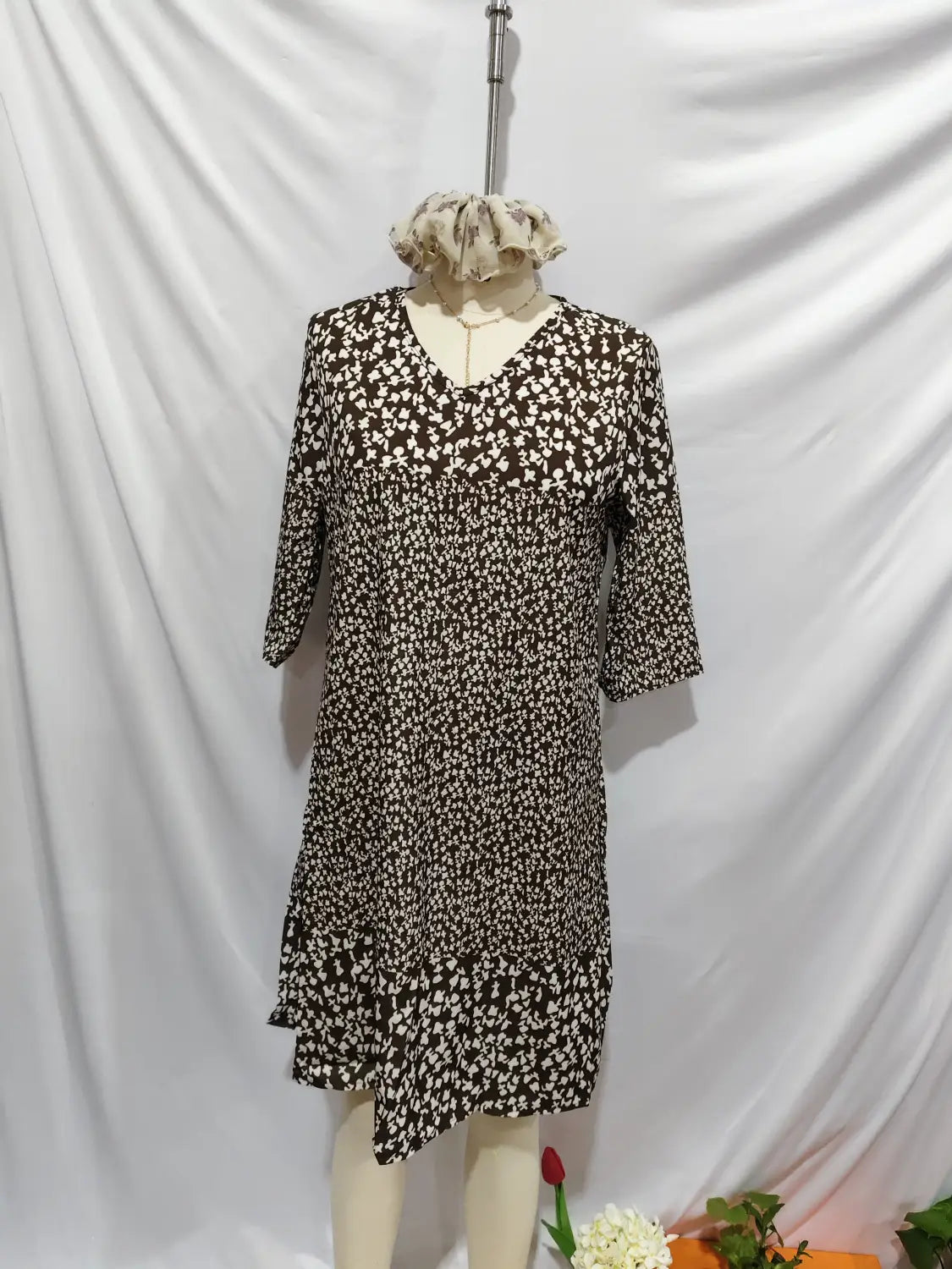 Une robe midi à imprimé floral noir et blanc, avec des manches trois-quarts, une encolure en V et une jupe évasée.