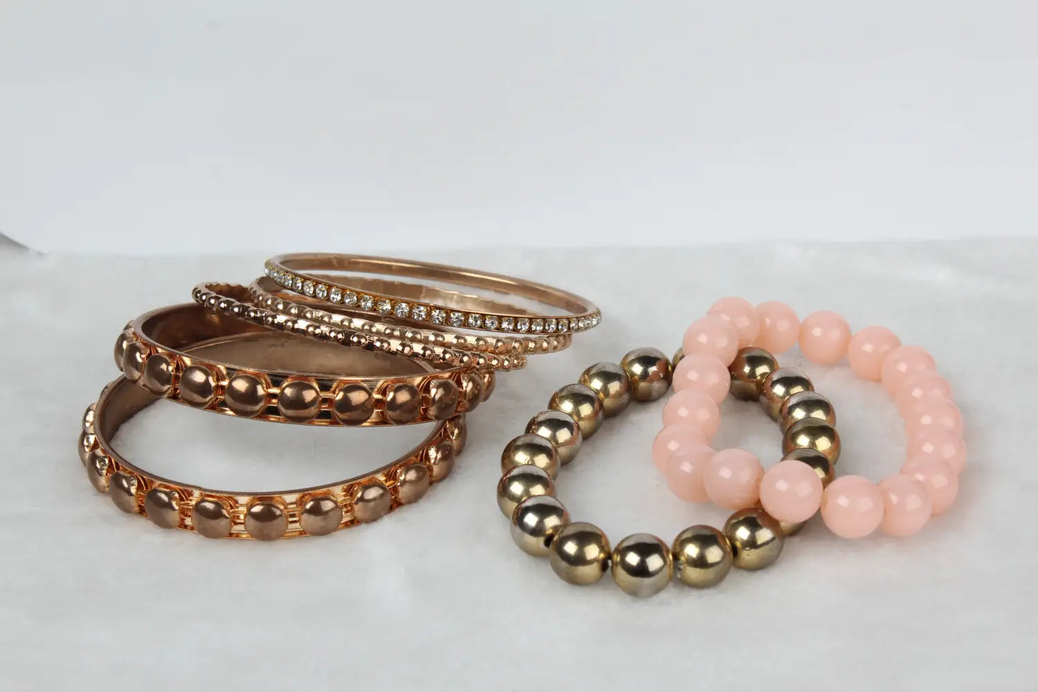 Set of rose gold and pink beaded bangle bracelets with metallic accents in a retro design.