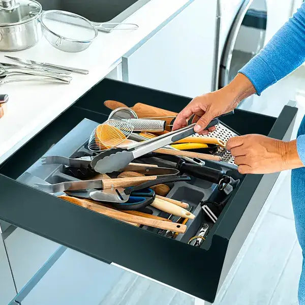 black kitchen utensil organizer made of carbon steel with molded compartments for pull out cabinet drawer storage holding various cooking tools