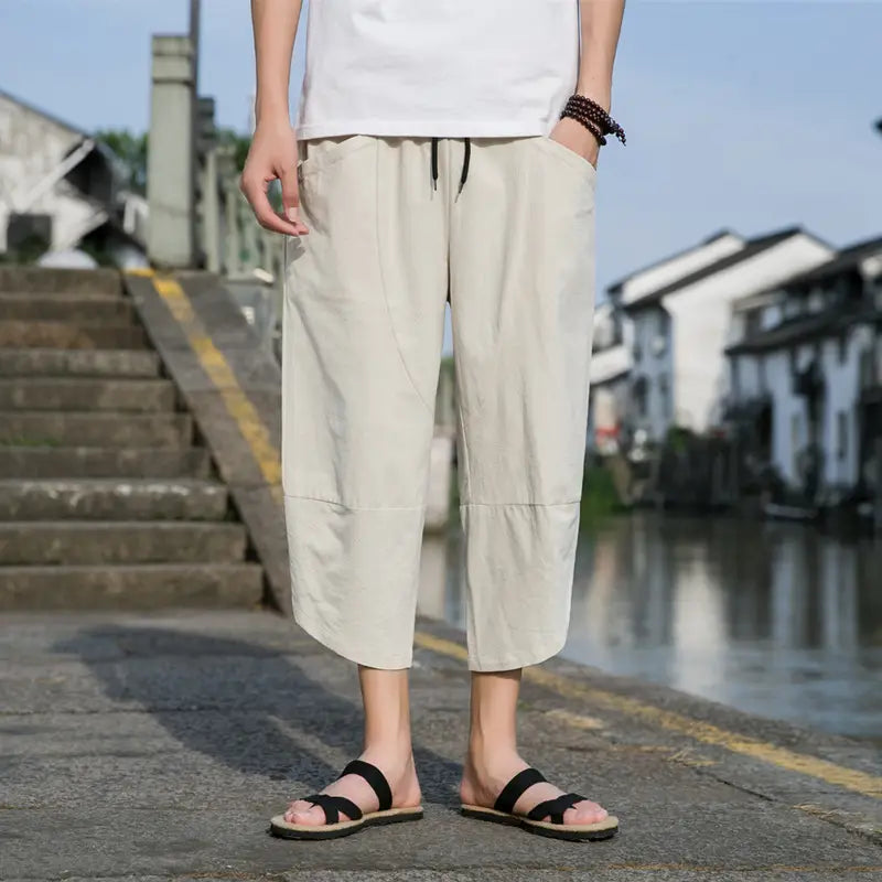 Pantalon de plage décontracté en lin beige pour hommes, avec bande de taille à cordon de serrage noire et bas retournés.