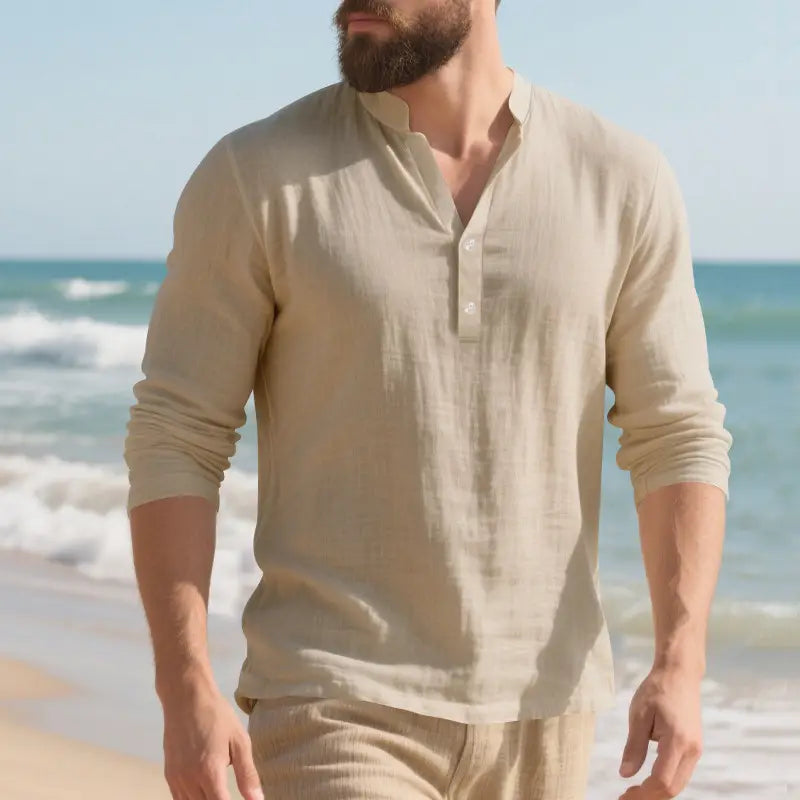 Camisa de lino color beige de manga larga tipo henley, con tapeta abotonada y puños arremangados, diseñada como pulóver informal para hombres.