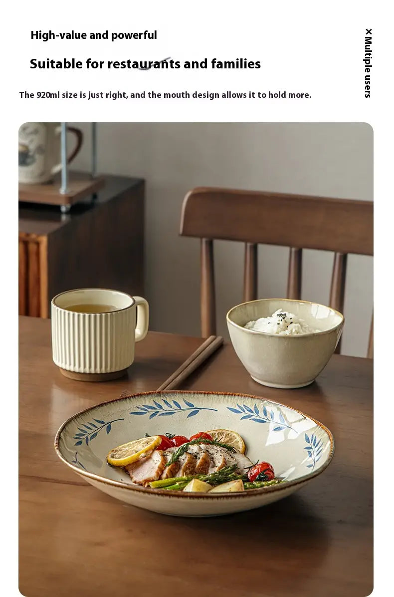 Cream-colored 9-inch ceramic deep plate with blue leafy pattern and rustic slightly chipped rim.
