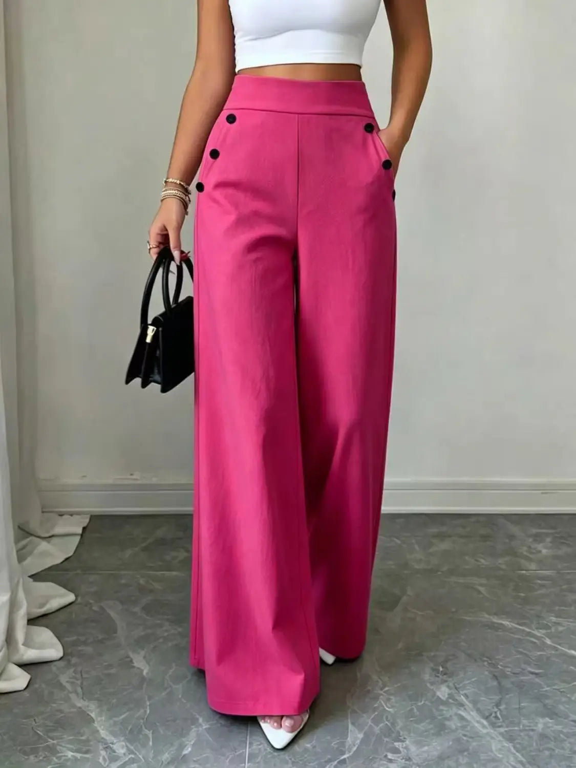 Pantalon ample taille haute fuchsia vif avec accents de boutons noirs, adapté à une tenue élégante et confortable.