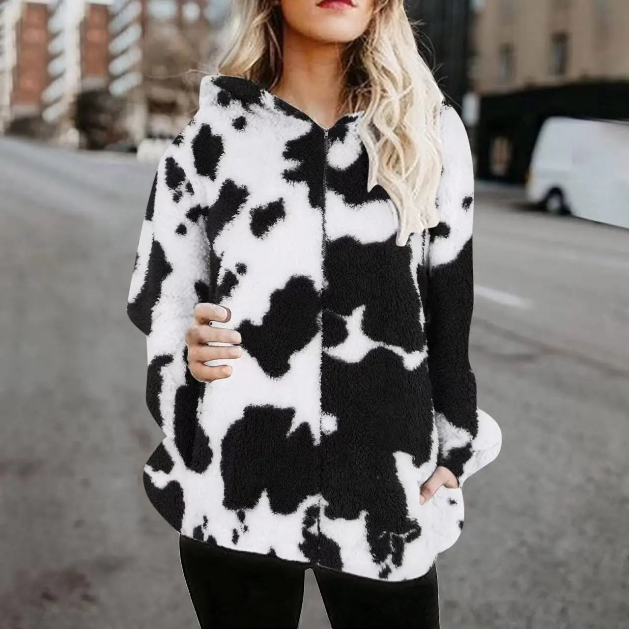 Chaqueta acolchada tipo zip-up con estampado de vaca, que presenta un diseño de vaca negro y blanco con un material de aspecto esponjoso con capucha para abrigar y brindar comodidad