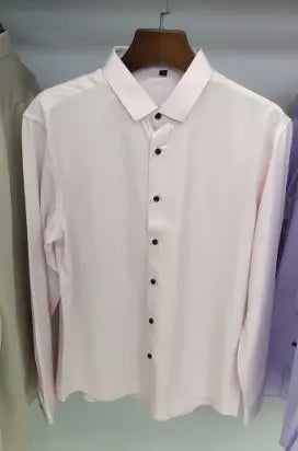 Ein frisches weißes Herrenhemd mit langem Ärmel, Slim Fit, aus glattem Stoff, mit klassischem Kragen und schwarzen Knöpfen, ordentlich auf einem hölzernen Kleiderbügel hängend.