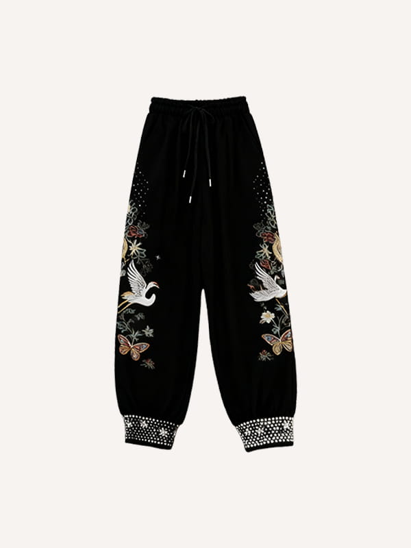 schwarze Samthose mit gesticktem Kranich und Straight-Leg-Fit, mit aufwendigem Weiß-Gold-Kranich-, Schmetterlings- und floralen Stickereien sowie funkelnder Strassstein-Verzierung an den Bündchen.