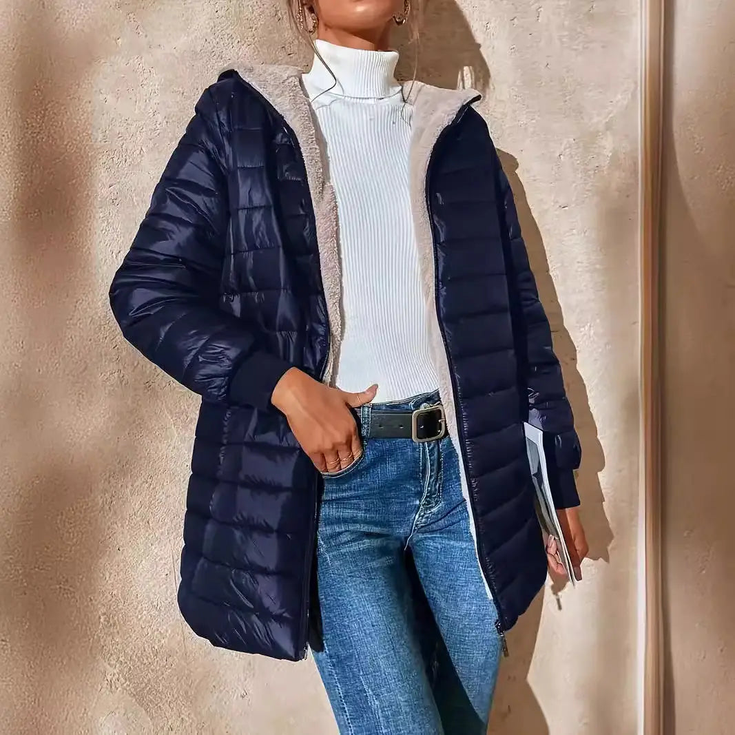 Doudoune matelassée bleu marine pour femme, avec capuche doublée en polaire et garniture en peau lainée gris duveteux, conçue pour vous tenir chaud.