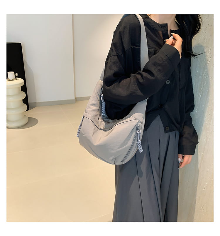 Light gray nylon crossbody bag with large capacity hobo shoulder style featuring a subtle textured finish and decorative blue patterned zipper pulls.