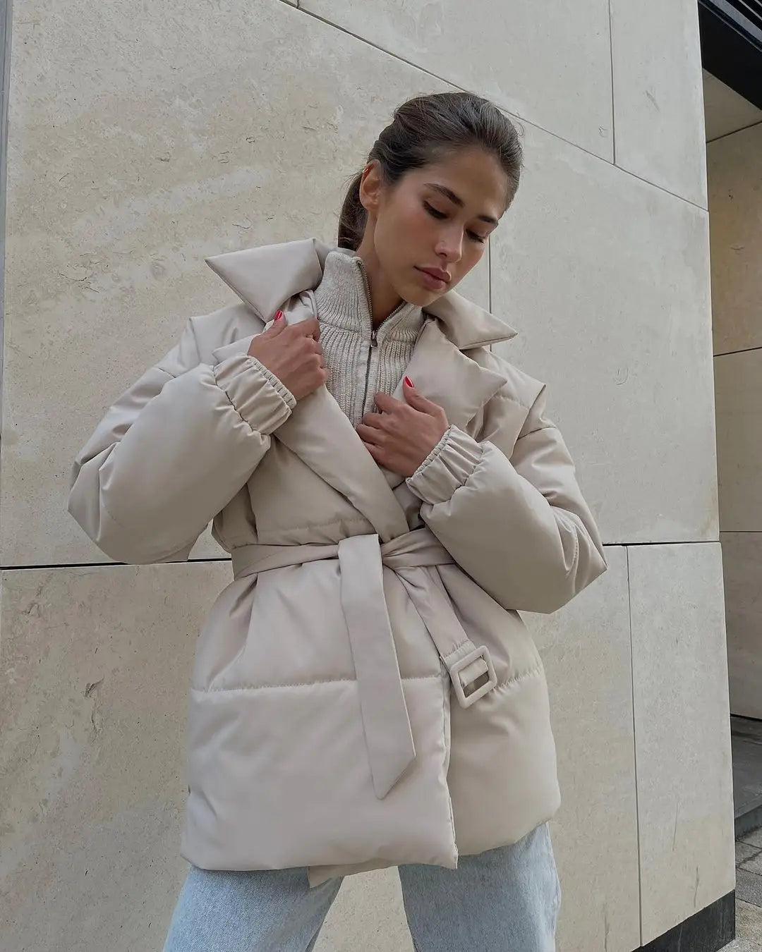 Beige Damen-Gurtsteppjacke mit Kapuze, wattierte Pufferjacke mit gerippten Bündchen, für Damenwinterjacke konzipiert.