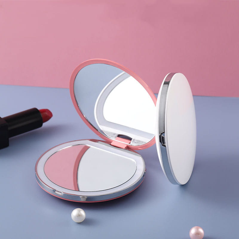 Espejo de maquillaje LED portátil compacto plegable USB en color rosa y plateado, con un diseño elegante y redondeado y un tamaño compacto para viajar y el uso diario