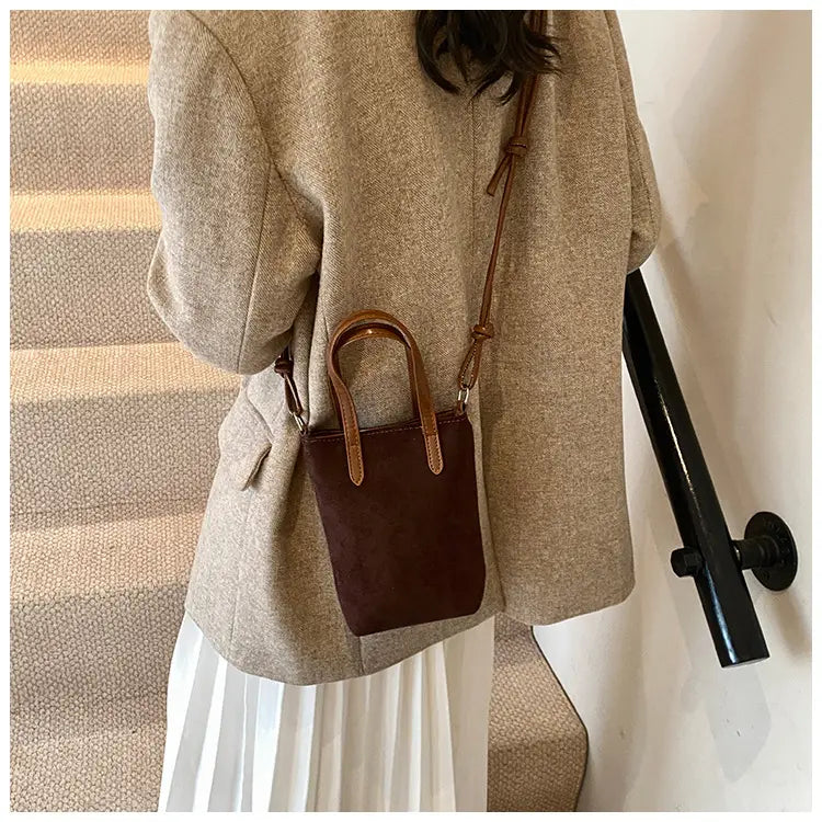 Brown suede mini bucket crossbody bag with matching leather handles and a retro leopard print design.