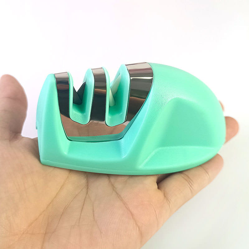 Affûteur de couteaux portatif à trois fentes en plastique turquoise et en acier inoxydable, maintenu dans la main pour l’affûtage de type souris.