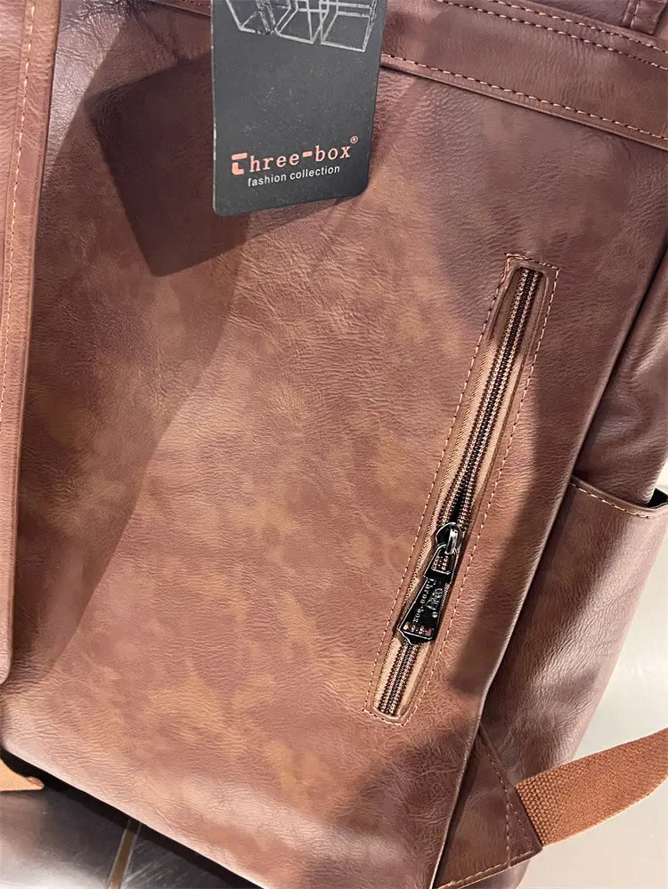 Brown faux leather vintage leather college backpack with large capacity and zipper pocket featuring a three-box fashion collection tag designed for travel use.