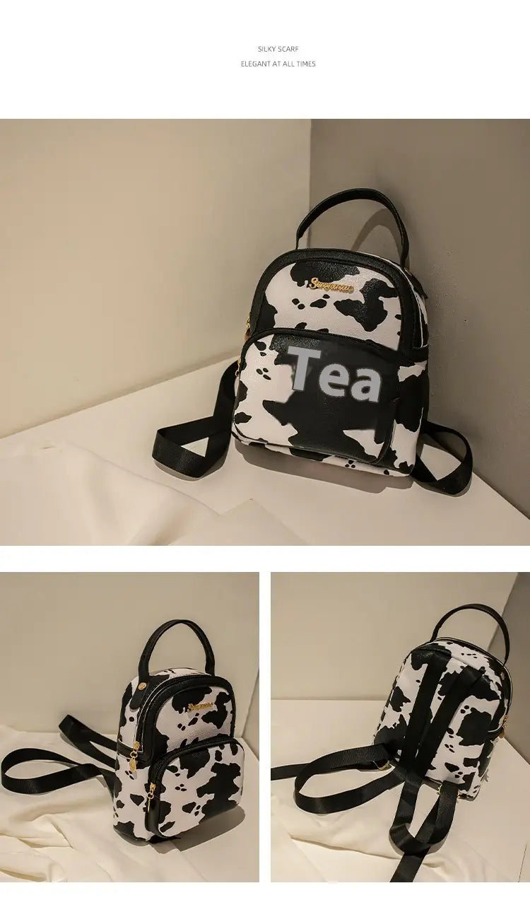 Mini backpack with black and white cow print featuring bold black tea lettering on the front in Korean style.