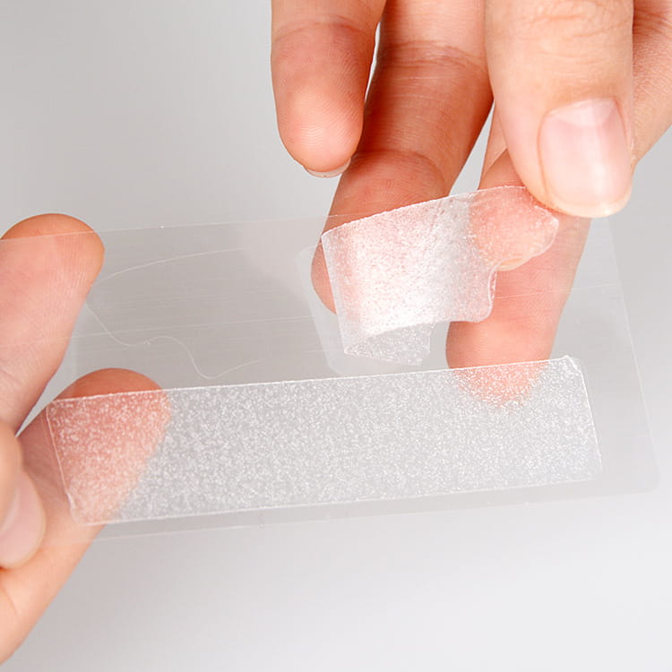 Tira adhesiva transparente con textura que se está retirando de su soporte en las tiras de blanqueamiento dental 5D del kit de atención dental menta de 14 unidades