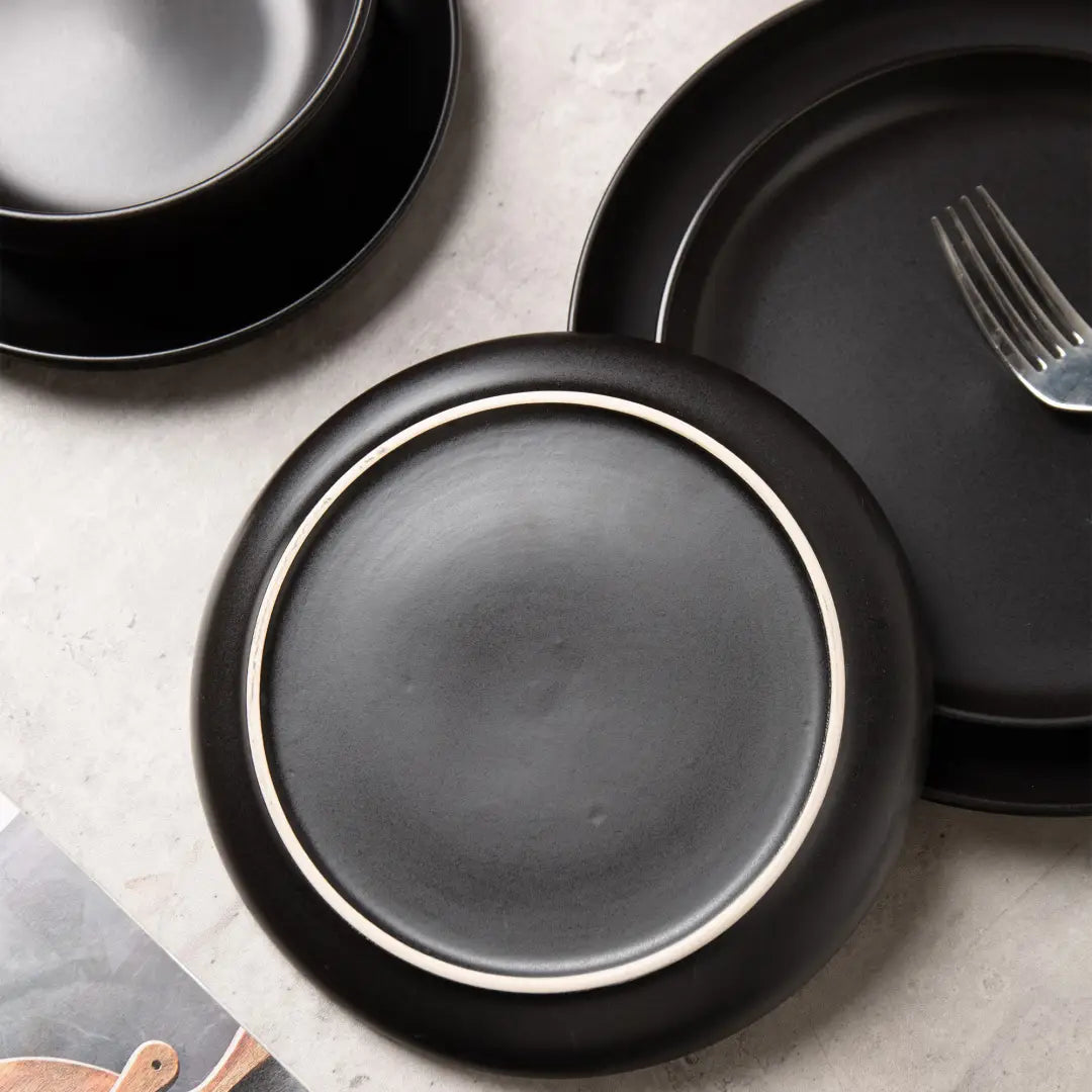 platos de cerámica negra con un sutil borde blanco, de un juego de vajilla de gres mate negro de 12 piezas diseñado para tres personas