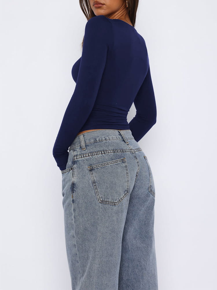 The back side of a pair of wide-leg light-wash denim jeans featuring a classic back pocket design paired with a leopard star print long sleeve crop top.