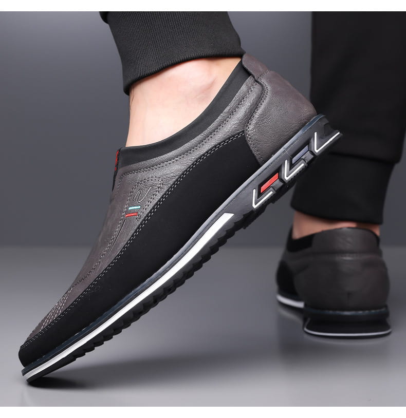 Mocasines de vestir de cuero para hombre, estilo casual de negocios, en negro y gris con detalles de acento rojo y suela de goma blanca.