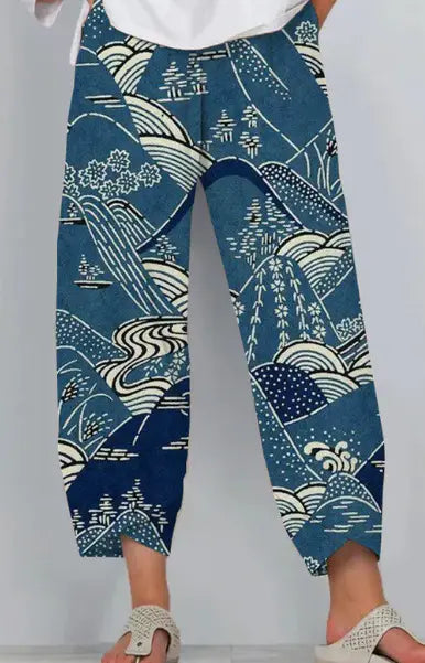 artistic printed and embroidered slimming cropped pants made of blue cotton featuring white and light blue wave mountain and tree patterns.