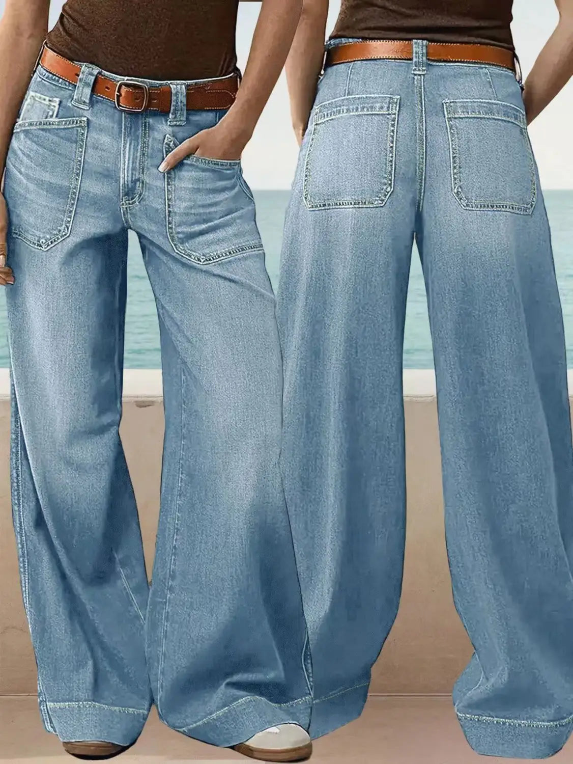 Light-wash denim wide leg pants with a brown leather belt displayed on a plain background.