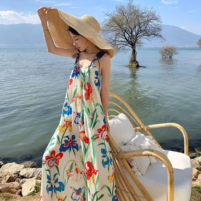 A woman wears a flowing off-white floral mesh maxi dress with vibrant red blue yellow and green patterns featuring a retro slip silhouette.