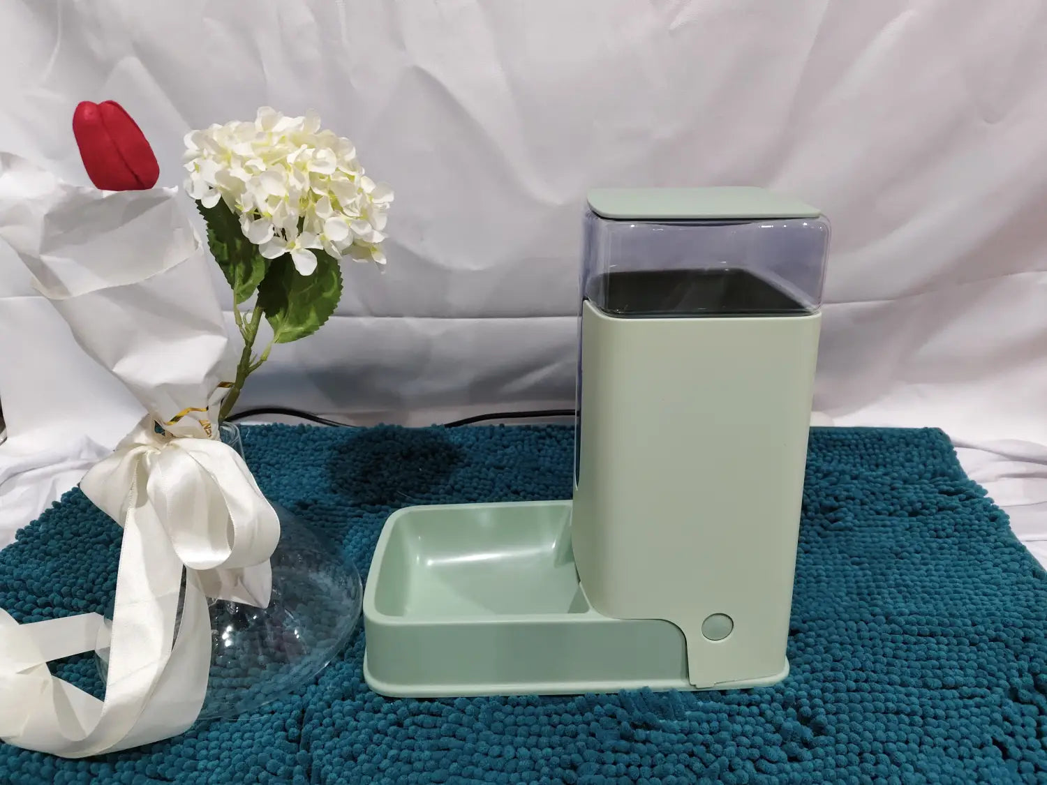 Mint green automatic pet feeder with clear plastic food compartment and matching tray for dispensing food and water.