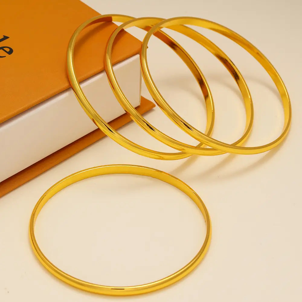 Set of four sleek polished gold colored 18k gold plated minimalist stackable bangles.