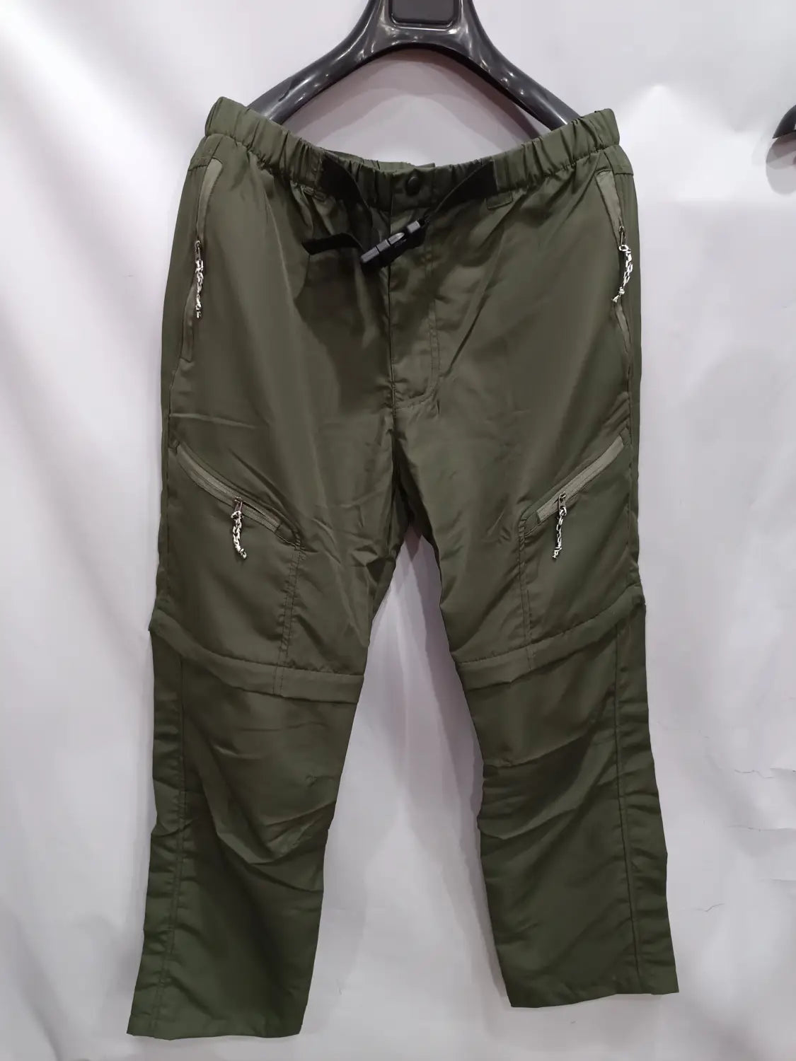 olive green convertible tactical hiking pants with multiple zippered pockets and an elastic waistband designed for outdoor use