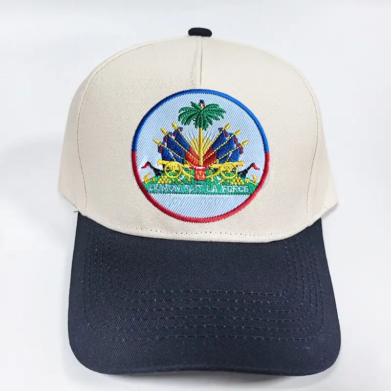 Beige and navy blue baseball cap featuring an embroidered circular patch of the Haitian national emblem with vibrant colors designed for sun protection.