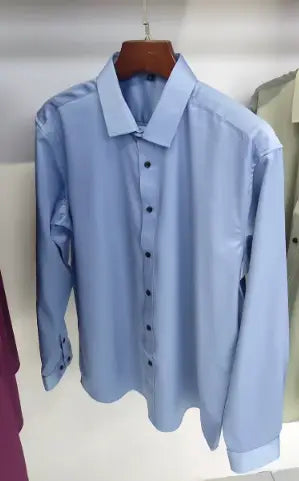 Herrenhemd mit langem Ärmel, Slim Fit, in Hellblau mit klassischem Kragen und Knopfverschlussfront, auf einem hölzernen Kleiderbügel hängend.